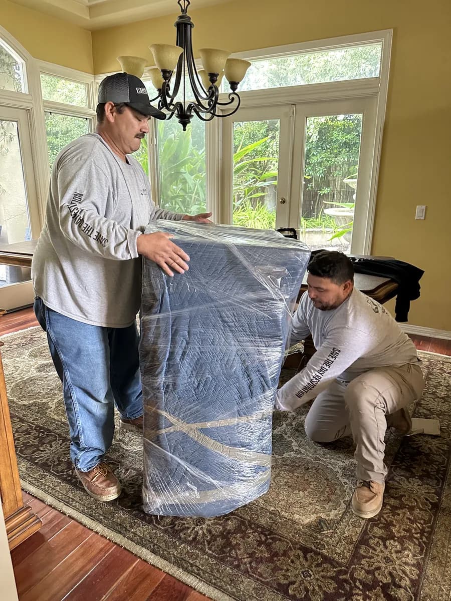 Two restoration crew members shrink-wrapping furniture during a contents pack-out