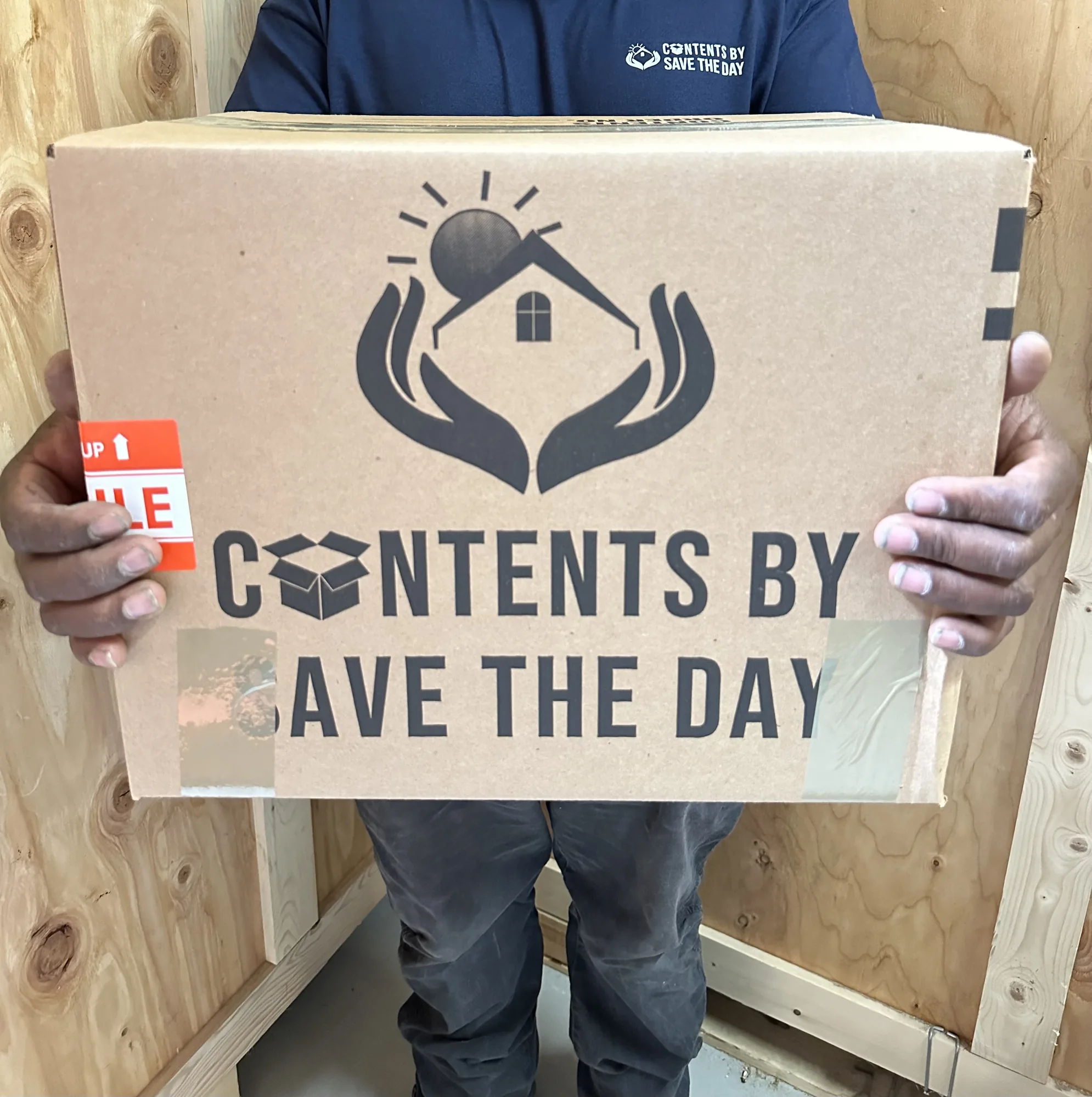 Contents by Save The Day technician holding a branded, fragile-labeled carton inside a storage vault
