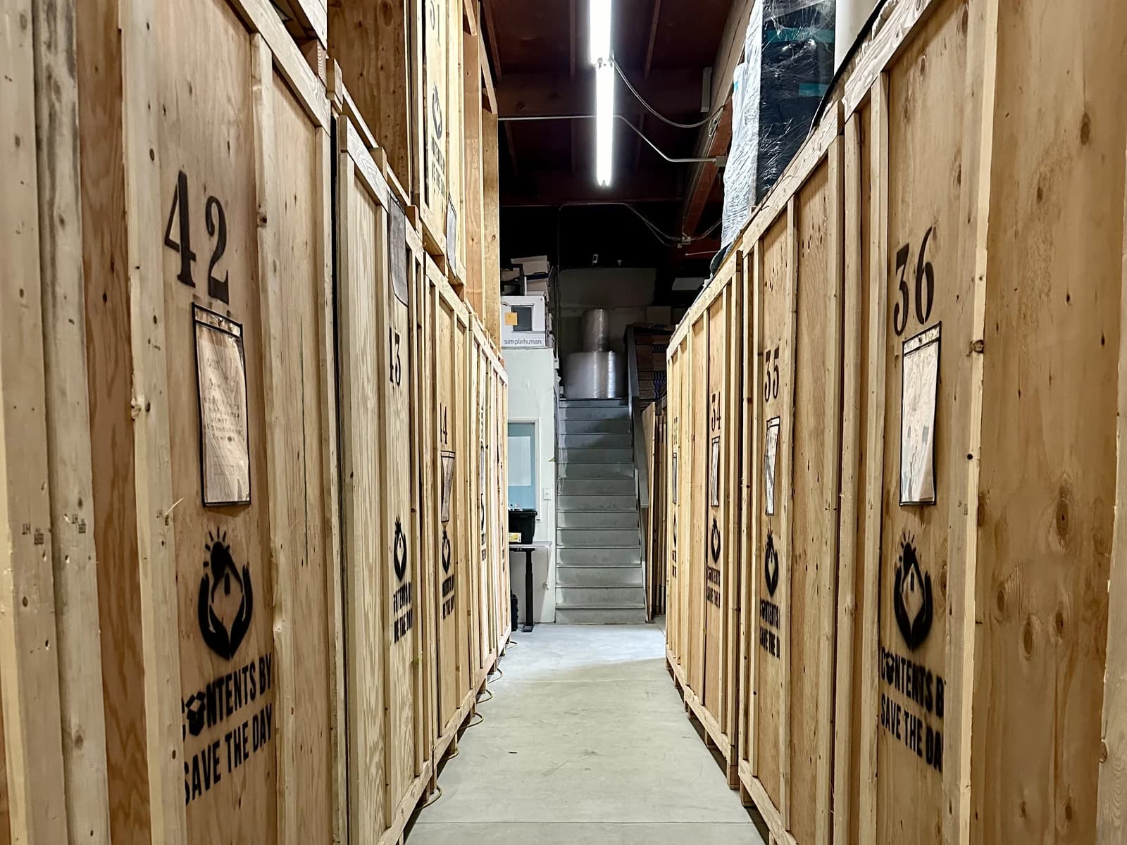 Aisle of numbered wood storage vaults, each stenciled with the Contents by Save The Day logo, at the Signal Hill facility