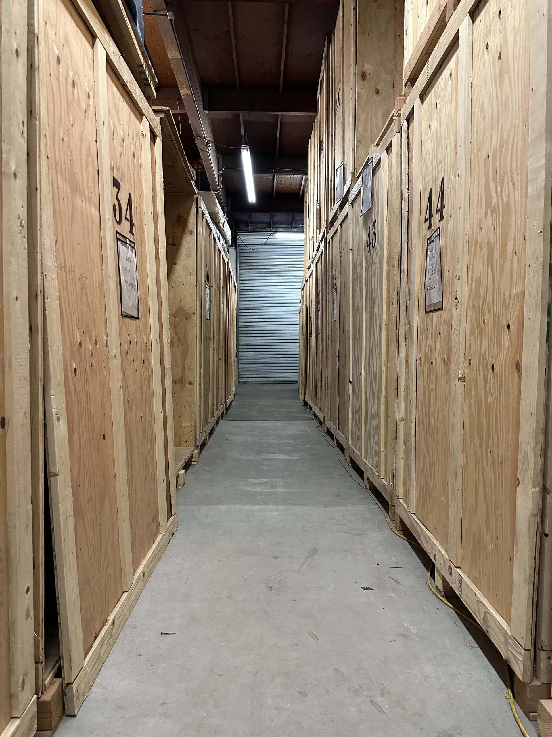 Warehouse aisle of numbered wood storage vaults with inventory tags at a contents storage facility